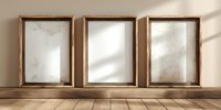 Three empty wooden frames with distressed mirrors standing on wooden floor, casting soft shadows on neutral wall background.