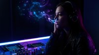 Young Caucasian female DJ in headphones exhales glowing neon smoke in dark studio with mixing console, creating vibrant nightlife atmosphere.