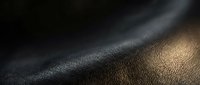 Luxury black leather texture with golden light reflection creating elegant surface pattern for premium fashion and interior design applications.