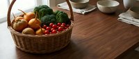 Wicker basket filled with fresh organic vegetables including tomatoes, onions, and leafy greens on wooden table for cooking and meal preparation.