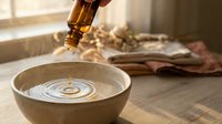 Essential oil drops falling into ceramic bowl creating ripples on water surface for aromatherapy spa treatment and natural wellness relaxation.