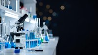 Modern laboratory with microscope and blue chemical solutions in test tubes for scientific research and medical analysis in professional lab setting.