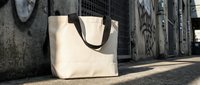 Beige canvas tote bag on urban street pavement against graffiti wall background. Eco-friendly shopping accessory for sustainable lifestyle and fashion.