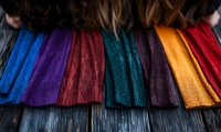 Vibrant colorful leather strips arranged in rows showing texture and grain detail, featuring blue, purple, red, green, gold and burgundy tones for fashion design.