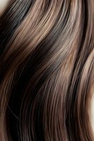Close-up of smooth, shiny brunette hair with caramel highlights showing texture and movement for beauty and haircare advertising.