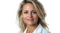 Confident middle-aged blonde woman in white blazer smiling at camera against white background, professional corporate headshot style portrait showing warmth and leadership.