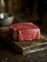 Raw beef steak on wooden cutting board in rustic kitchen setting ready for cooking and grilling preparation.