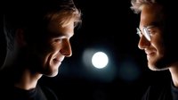 Two young men facing each other in dramatic lighting with bright light source between them creating silhouette effect for business teamwork concepts.