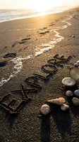 Word explore written in wet sand at sunset beach with seashells and vintage compass, ocean waves in background, travel and adventure concept.