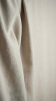 Natural linen fabric texture with soft folds and creases in neutral beige tones. Organic cotton material background for interior design and textile projects.