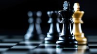 Black and white chess pieces on board with dramatic lighting, king piece in focus against dark background showing strategy and leadership concept.