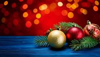 Festive Christmas ornaments with gold and red baubles on blue wooden surface against blurred bokeh lights background.