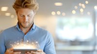 Young caucasian businessman in blue shirt using digital tablet with glowing magical light effect emerging from screen, bokeh background, technology concept.