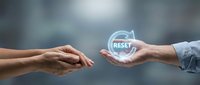 Business professional offering reset button symbol to colleague representing fresh start and new beginning opportunities in corporate environment.