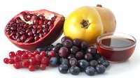 Fresh seasonal berries and fruits with pomegranate, quince and glass of juice on white background, healthy organic antioxidant food composition.