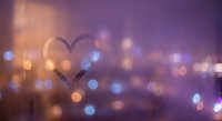 Heart shape drawn on foggy glass window with romantic bokeh lights background creating dreamy atmosphere for love and relationship concepts.