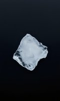 Single ice cube with crystal clear transparency and natural texture isolated on dark background for beverage and cooling concepts.