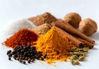 Colorful aromatic spices arranged on white background - turmeric, paprika, salt, cinnamon sticks, cardamom pods, black peppercorns, and nutmeg.