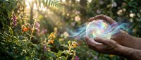 Hand holding glowing orb of light energy in lush garden with ferns and flowers, representing nature power, healing, and spiritual growth for wellness and environmental concepts.