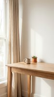 Minimalist wooden desk with coffee mug and small succulent plant by window with beige curtains in bright natural light for home office workspace design.