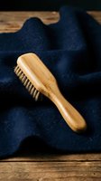 Natural bamboo hair brush with boar bristles on dark blue towel for eco-friendly grooming and sustainable beauty routine.