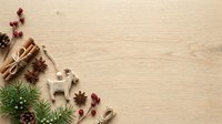 Flat lay composition with cinnamon sticks, star anise, dried berries, and evergreen sprigs arranged on light wooden surface for holiday and seasonal design projects.
