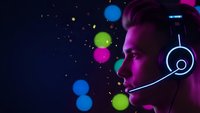 Young male gamer with headset in neon lighting playing video games with colorful bokeh lights background for streaming and esports content.