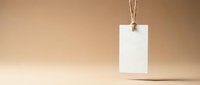 Blank white paper tag hanging from natural twine string against warm beige background for product labeling and branding mockup designs.