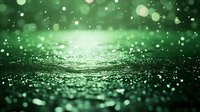 Magical green glitter background with bokeh lights and sparkles on dark surface. Defocused abstract festive backdrop with shallow depth of field.