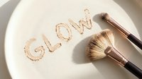 Makeup brushes with rose gold ferrules arranged on white plate with glow text written in shimmering powder, cosmetics and beauty product styling for makeup artist tutorials and skincare branding.
