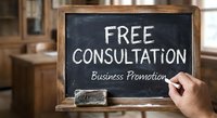 Free consultation business promotion written on blackboard with hand holding chalk in professional office setting for marketing and customer service.