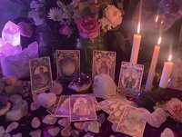 Mystical tarot card reading setup with glowing candles, rose bouquet, crystals and scattered cards on dark surface creating magical divination atmosphere.