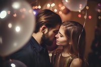 Romantic couple sharing intimate moment at party with bokeh lights background, young woman in gold dress and bearded man about to kiss in atmospheric lighting.