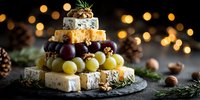Festive cheese tower with grapes and nuts on slate board, holiday appetizer platter with warm bokeh lights background for entertaining and celebrations.