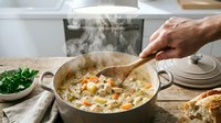 Professional chef stirring creamy risotto in stainless steel pan with wooden spoon. Steam rising from hot Italian rice dish in modern kitchen setting.