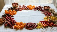 Colorful dried chili peppers and spices arranged in circular frame on white marble surface creating natural border for food photography and culinary designs.