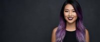 Young Asian woman with purple ombre hair smiling confidently against dark background for beauty and fashion marketing campaigns.