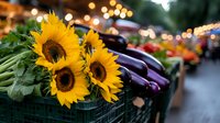 Fresh sunflowers and purple eggplants at farmers market stall with bokeh lights in background, local organic produce and seasonal flowers for sale.
