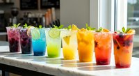 Colorful summer cocktails and mocktails in glasses with fresh fruits and mint garnish arranged on kitchen counter for refreshing beverages and party drinks.