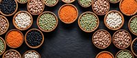 Assorted legumes and pulses in wooden bowls arranged on dark slate surface, overhead view for cooking and nutrition content.