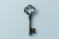 Vintage ornate metal key with quatrefoil bow design isolated on light blue background, symbolizing security, mystery and access. Perfect for design projects.