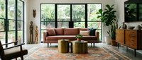 Modern living room with terracotta sofa, brass cylindrical tables, wooden furniture, potted plants, and large windows overlooking greenery for interior design and home decor projects.