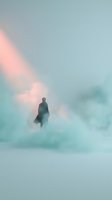 Silhouetted male figure standing alone in dense fog and mist with soft peachy light rays breaking through clouds, evoking mystery and solitude for conceptual and editorial use.