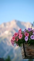 Colorful petunias in rustic wooden hanging basket against blurred mountain landscape background on sunny day for garden and outdoor decoration concepts.