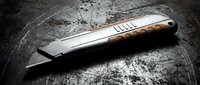 Professional folding knife with wooden handle and steel blade on weathered metal surface. Sharp tactical tool for outdoor activities, camping, and everyday carry use.