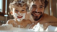 Father and son having fun during bath time, playful moment with soap bubbles and foam, warm lighting creates cozy atmosphere in bathroom.