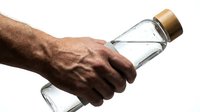 Man with dark skin tone holding clear water bottle with cork cap against white background, isolated for design use on promotional materials, wellness campaigns, and hydration product marketing.