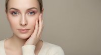 Young Caucasian woman with natural makeup touching face gently, skincare and beauty concept for cosmetic products and wellness treatments.