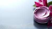 Pink luxury face cream in glass jar with orchid flower on gray background, cosmetic skincare product photography with copy space for beauty industry.