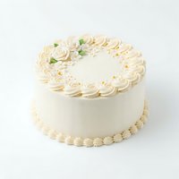 Elegant cream-colored layer cake with piped frosting borders, fondant roses, and gold leaf accents on white background. Perfect for bakery, wedding, and celebration designs.